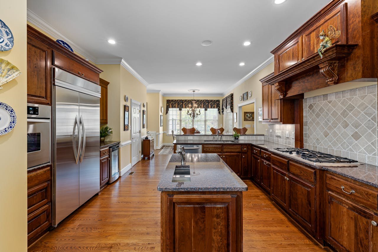 Modern kitchen with wooden cabinets and granite countertops, featuring stainless steel appliances.