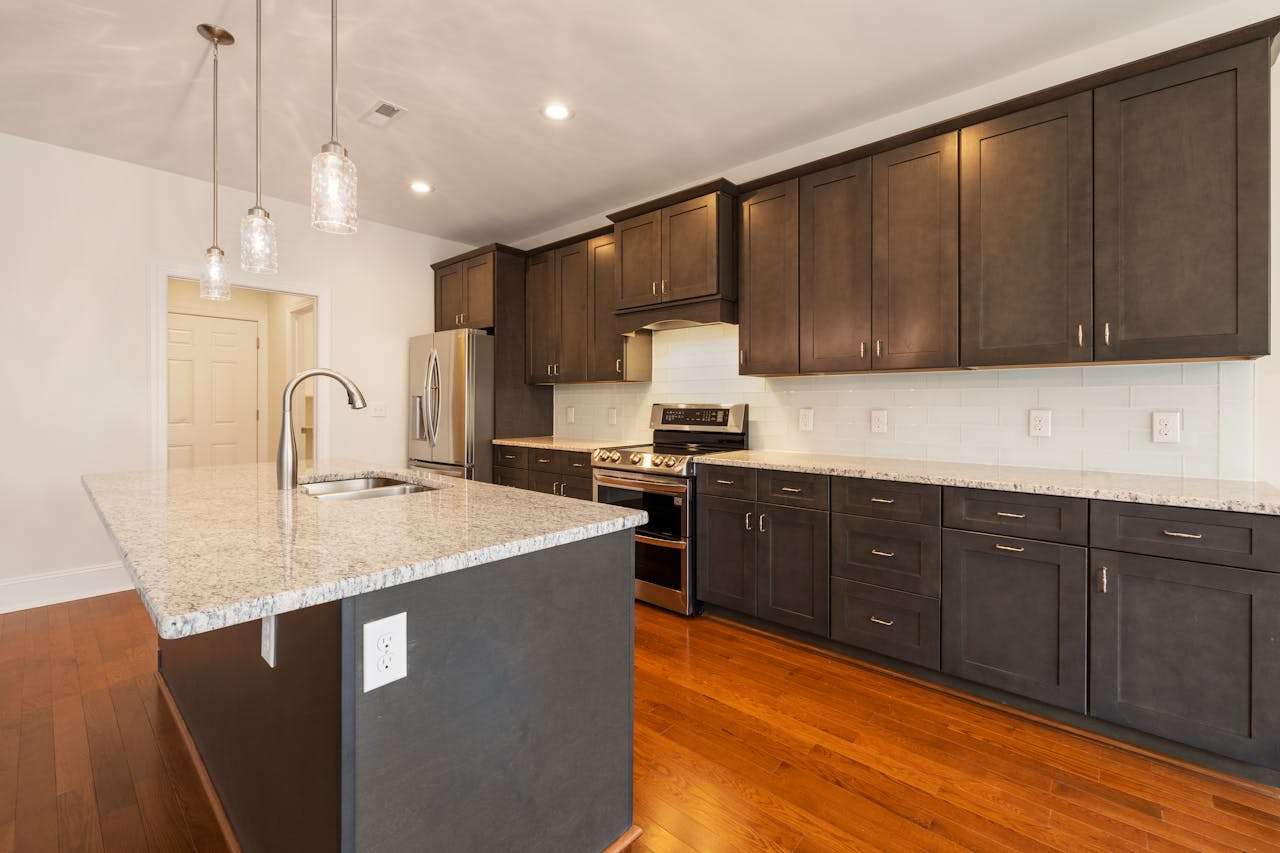 Spacious modern kitchen featuring a granite island, stainless steel appliances, and hardwood floors.